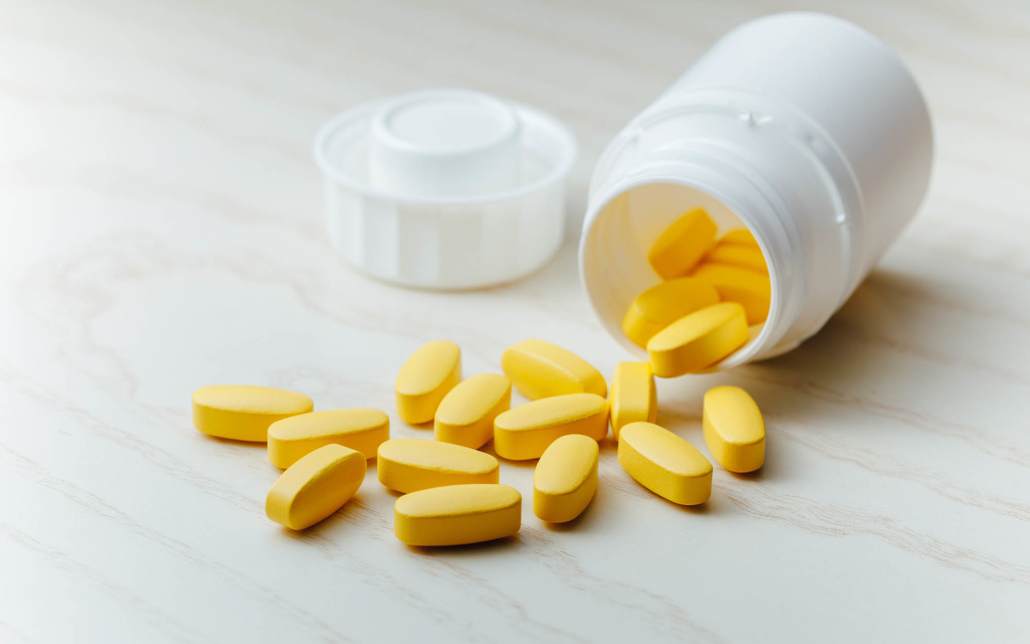 Close up view of an open bottle of yellow coated tablets