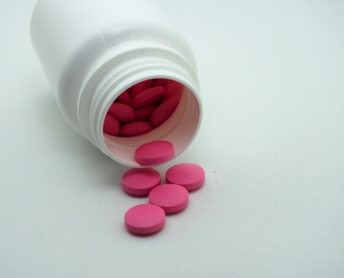 View of pink-coated tablets falling out of a medicine bottle