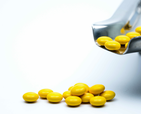 View of yellow-coated tablets falling out out of a perforated coating pan